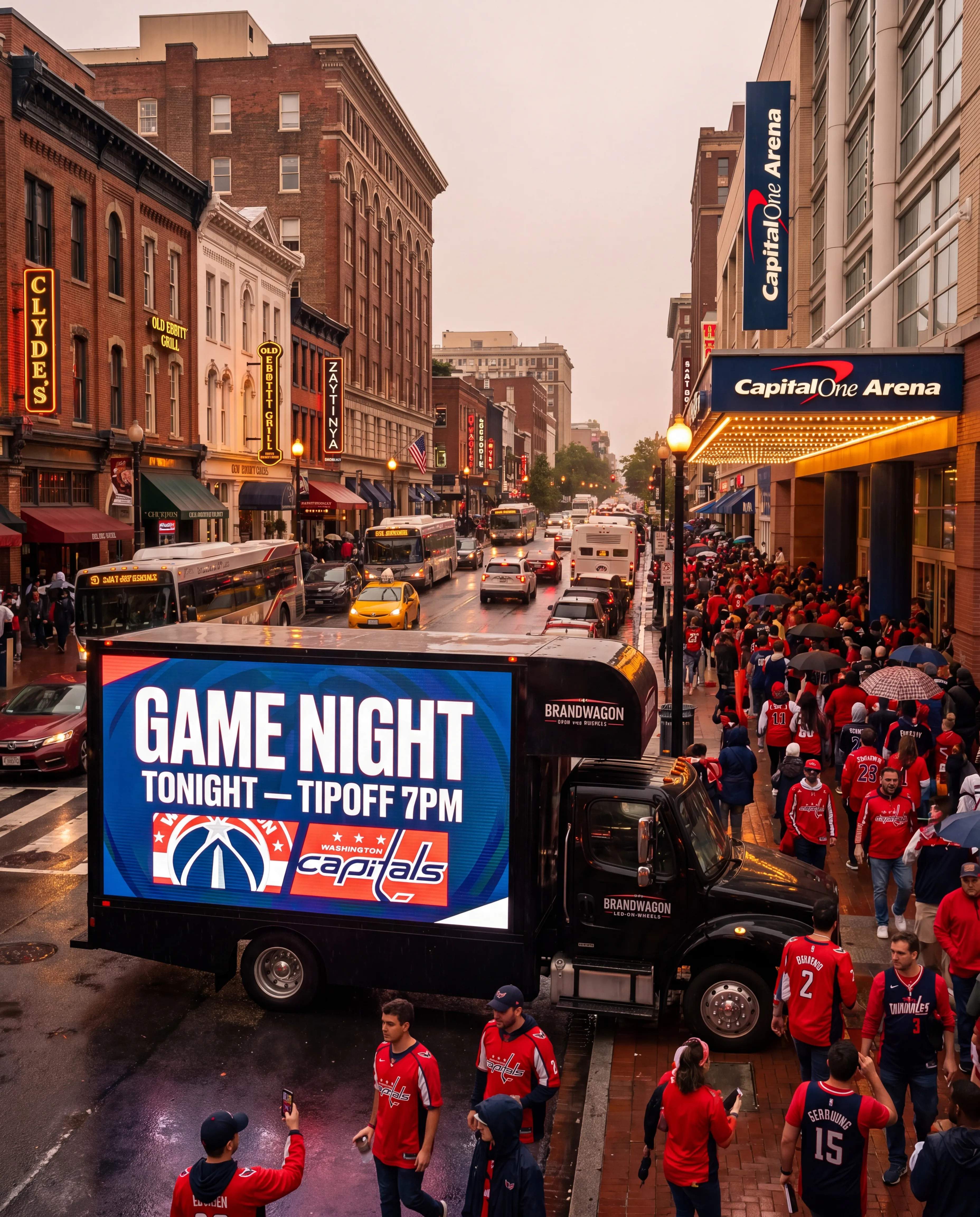 Brandwagon LED billboard truck outside Capital One Arena in Penn Quarter Washington DC on a packed Capitals game night with fans in red jerseys and the Old Ebbitt Grill and Clyde's neon signs visible